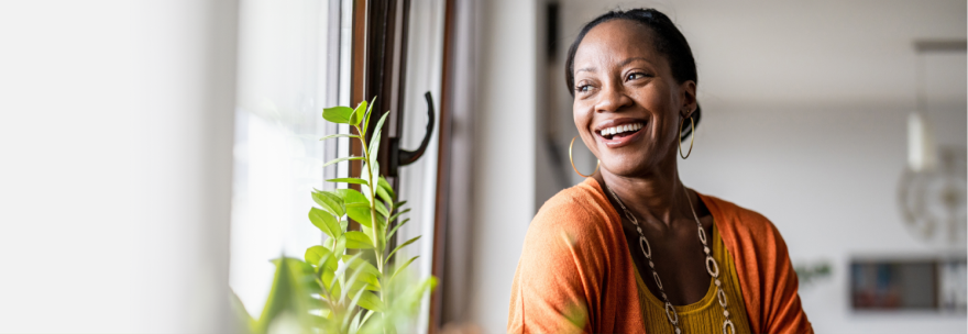 A cheerful woman sits by a window