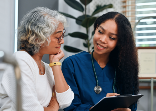 A patient and health care provider engage in conversation while reviewing information on a clipboard
